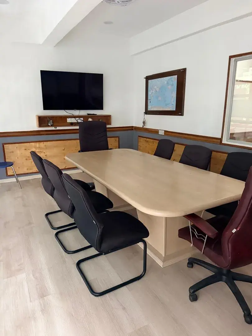 A long conference table and chairs in the firm's meeting room, with a wall-mounted screen