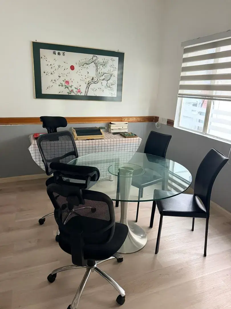 A round glass table and office chairs in a consultation room, beside a window with blinds